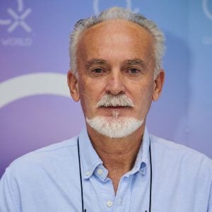 Elderly man in blue shirt speaking at conference