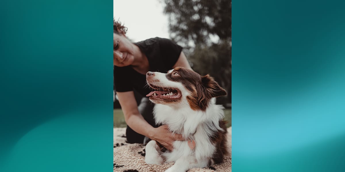 Woman cuddling brown and white dog outdoors